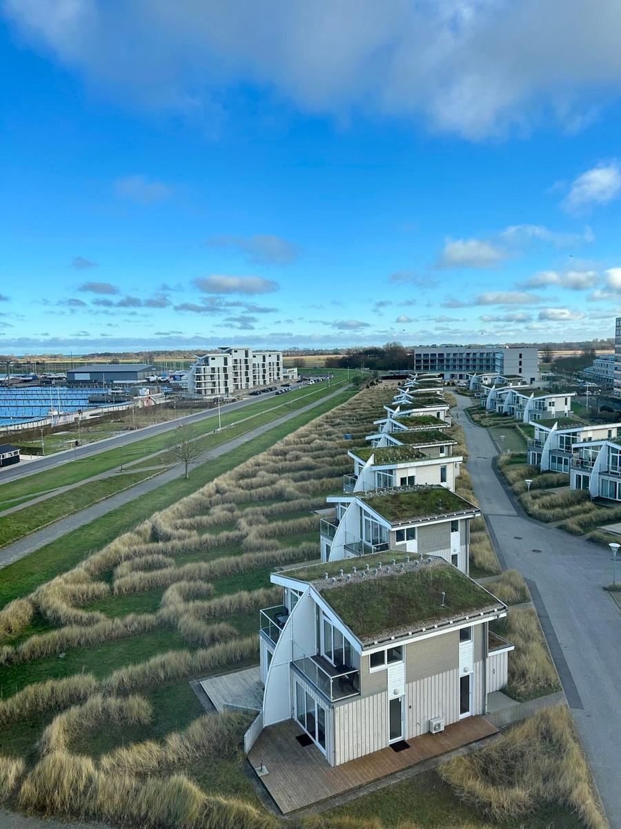 Modernes Ferienhaus mit Grasdach und Balkon. Blick auf Wasser und Strand.