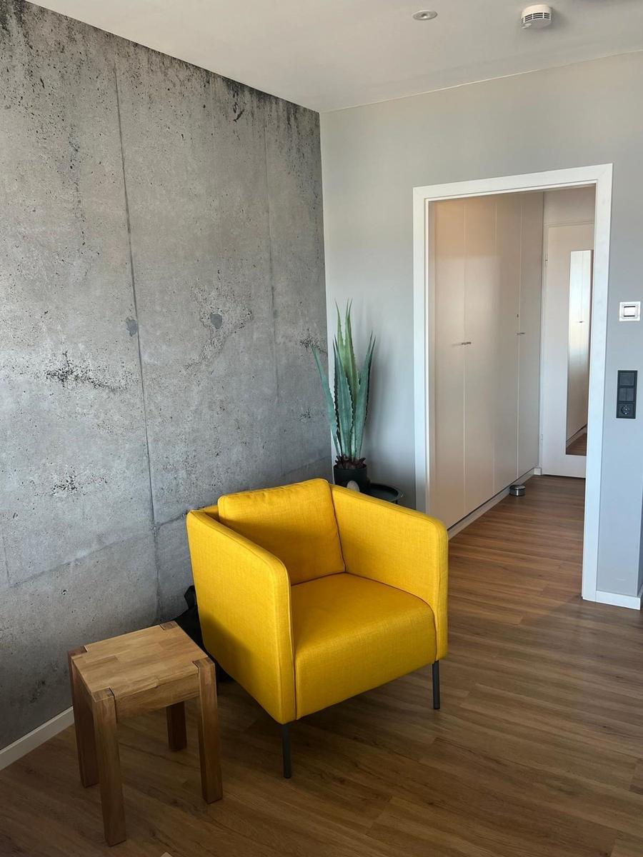Gelber Sessel neben Betonwand und Holzboden