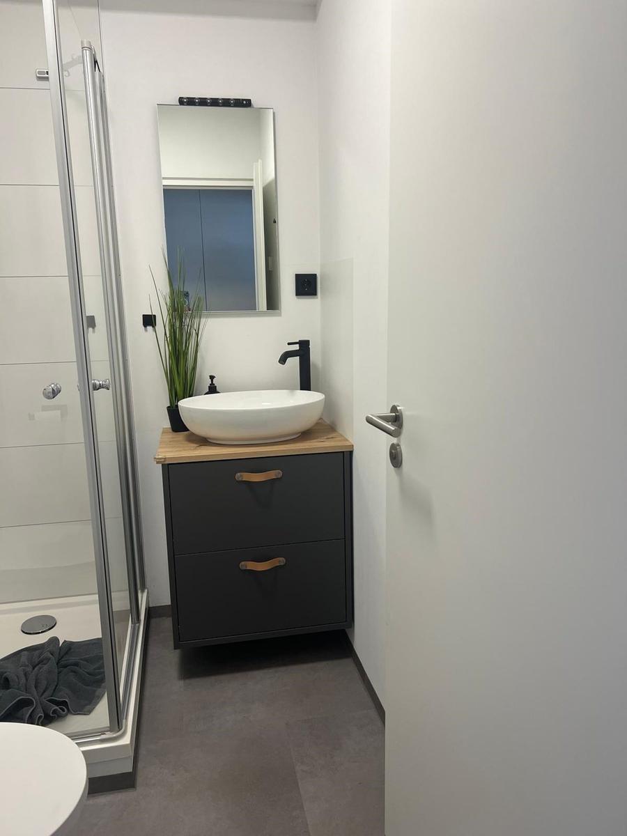 Badezimmer mit Dusche, Waschbecken und Spiegel