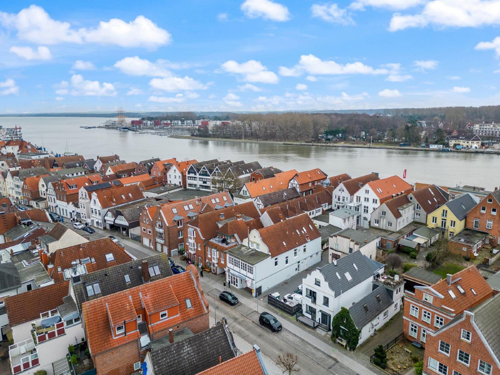 Panoramablick auf einen Fluss mit Häusern und Booten am Ufer.