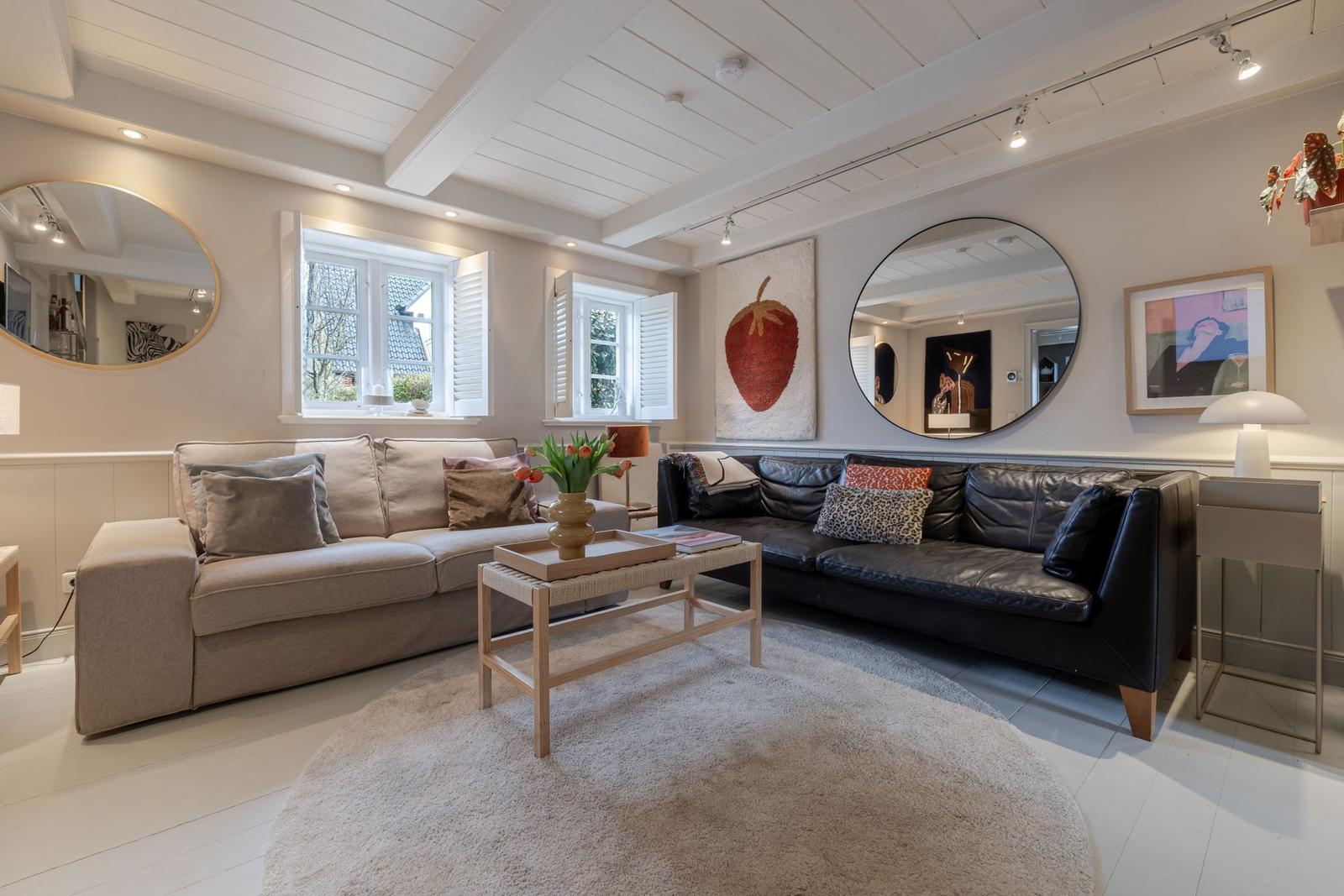Wohnzimmer mit zwei Sofas, runden Spiegeln und einem großen Teppich.