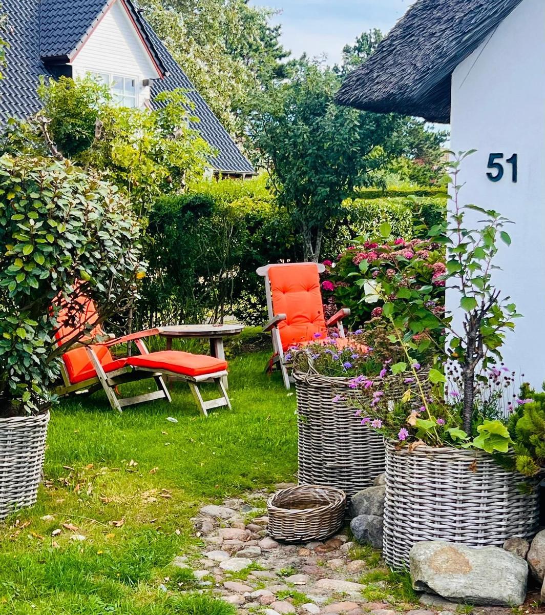 Garten mit orangefarbenen Sitzgelegenheiten und Pflanzen in Körben.