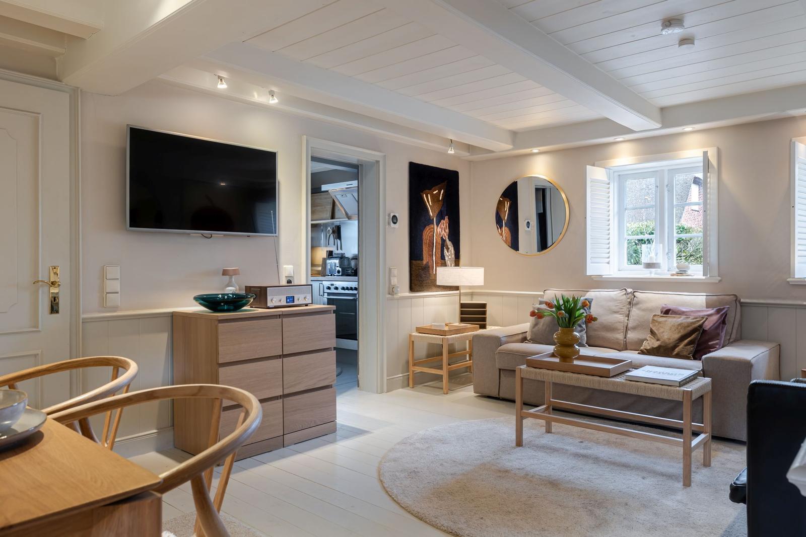 Wohnzimmer mit Sofa, Fernseher und Küchenbereich