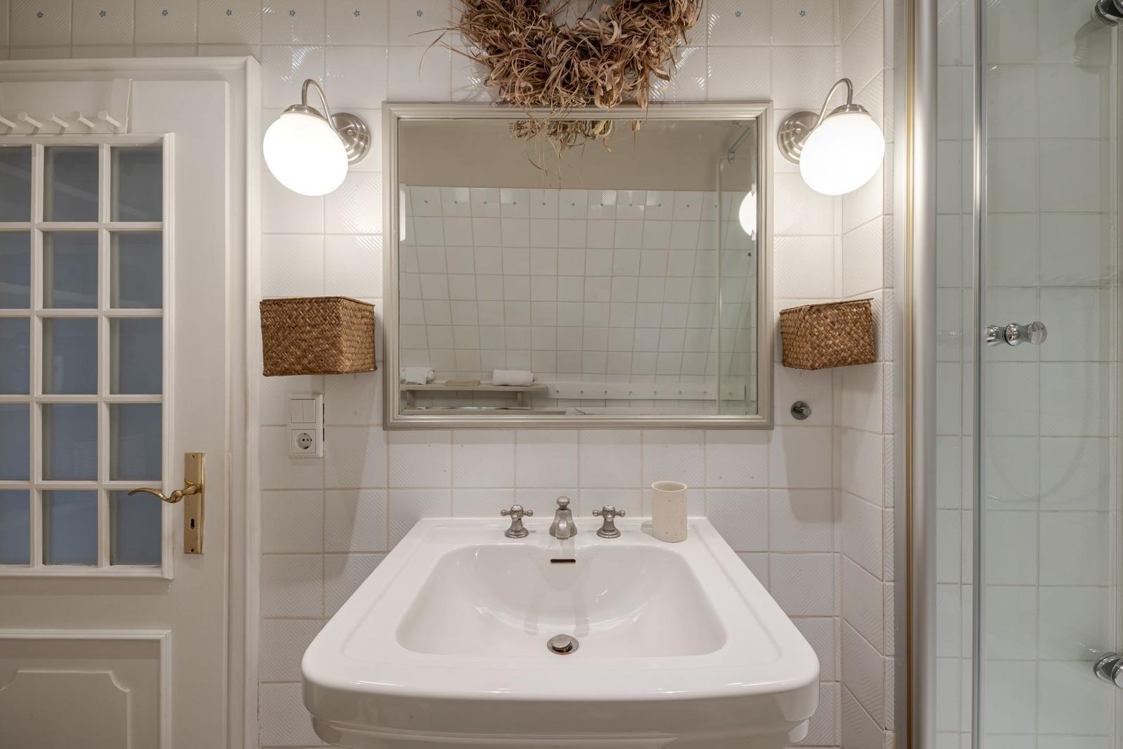 Badezimmer mit Waschbecken, Spiegel und Dusche