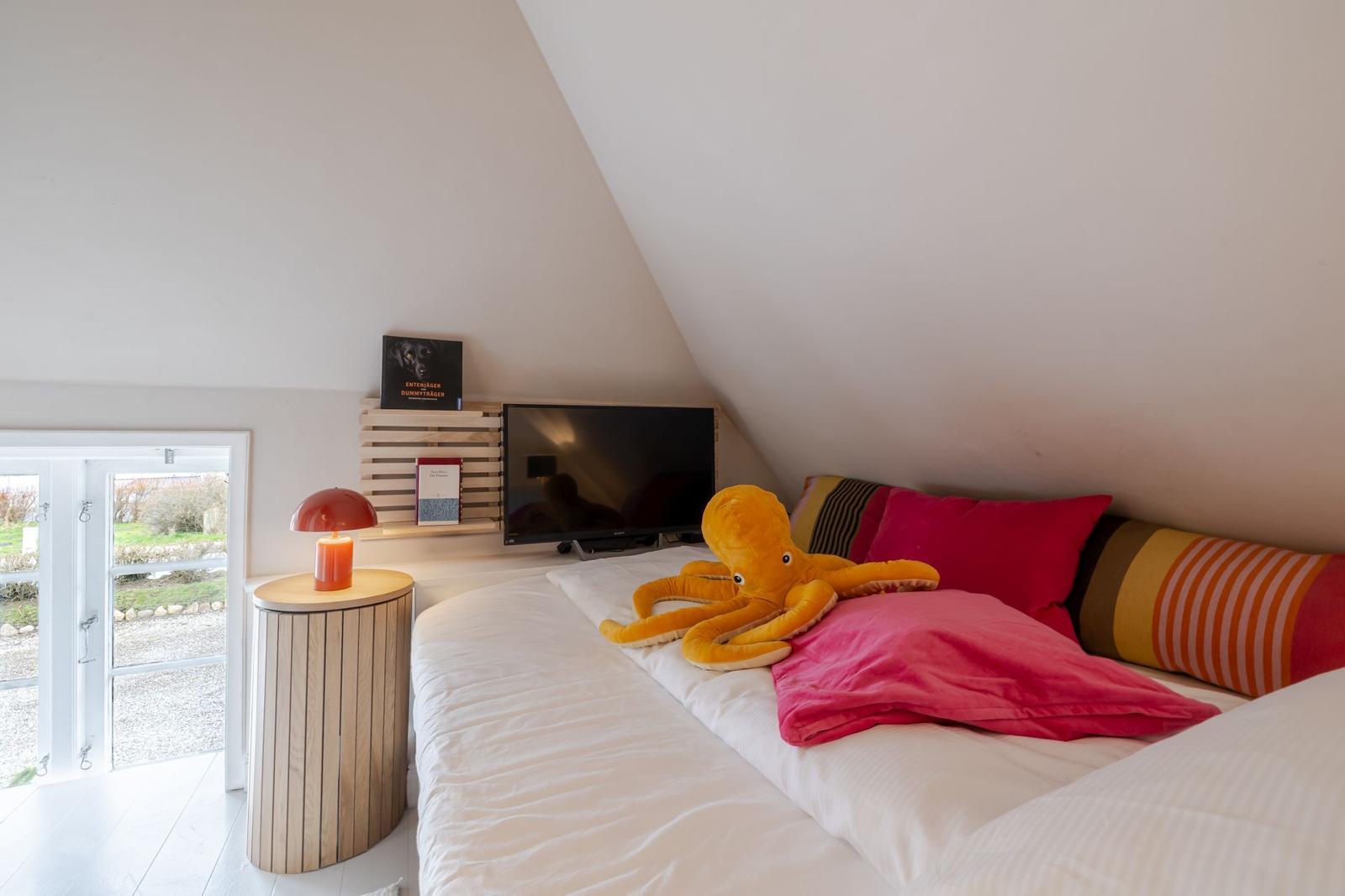 Schlafzimmer mit Bett, Fernseher und Blick auf Außenbereich.