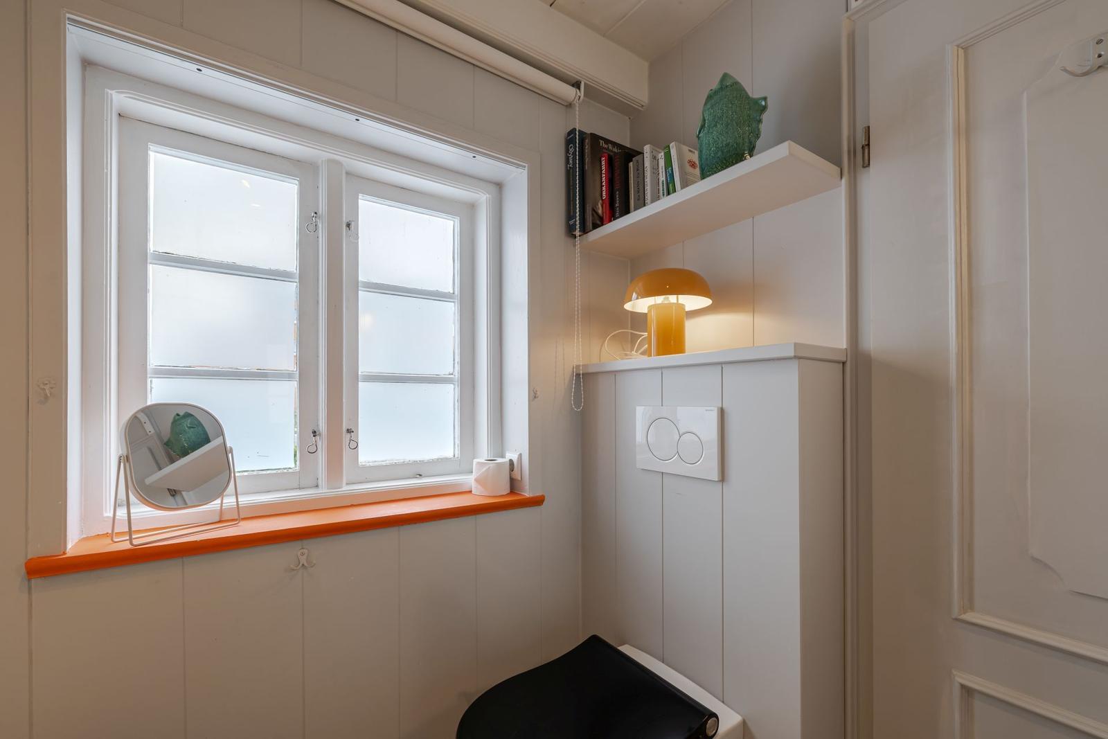 Badezimmer mit Fenster, Spiegel und Nachttischlampe.