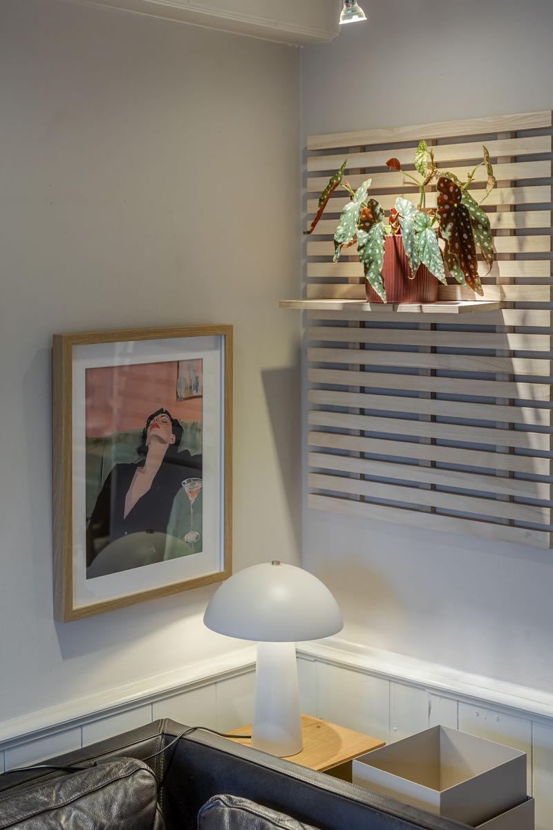 Wohnzimmer mit Pflanze, Lampe und Bild an der Wand.