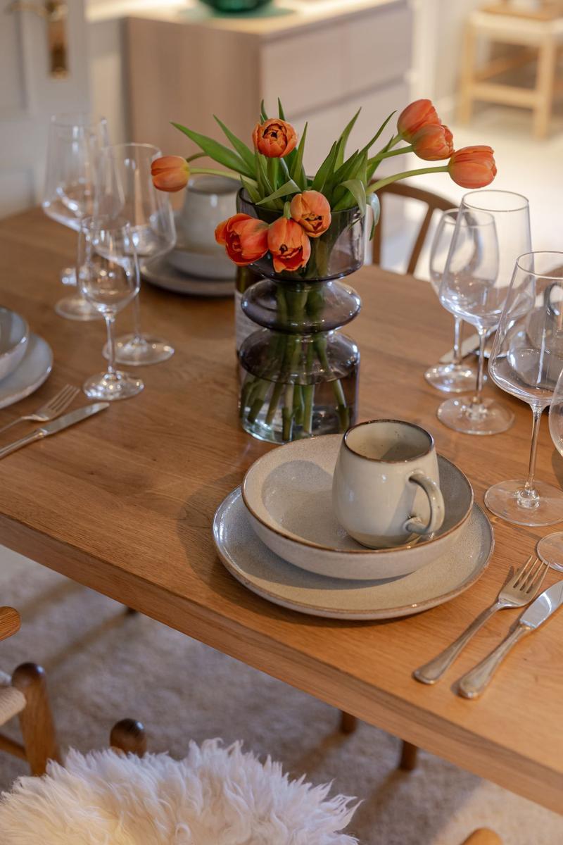 Holztisch mit Tischdekoration und orangefarbenen Tulpen.