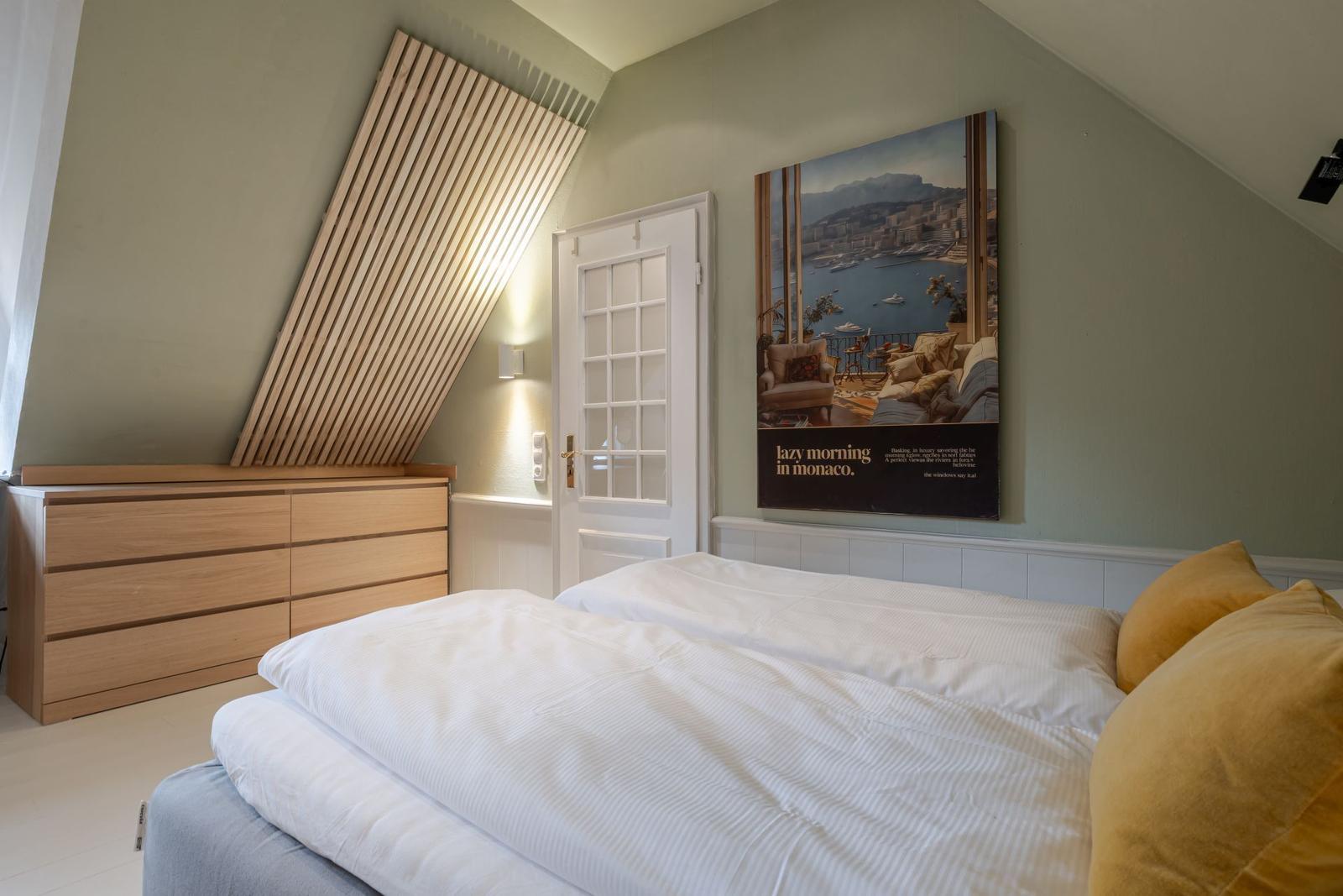 Schlafzimmer mit Doppelbett, Holzschrank und Wandbild Monaco.