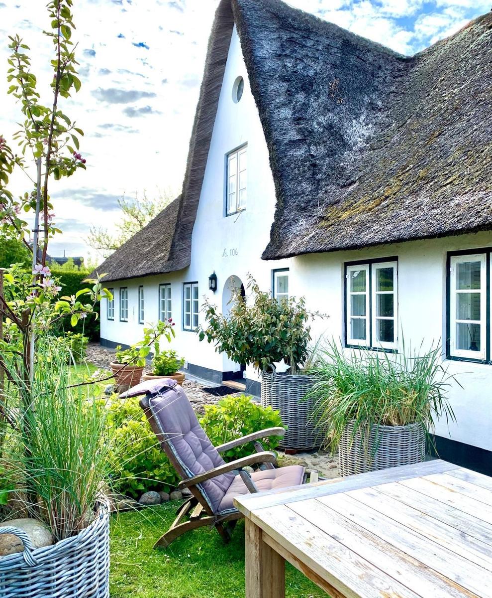 Haus mit Strohdach, Garten mit Liegestuhl und Tisch