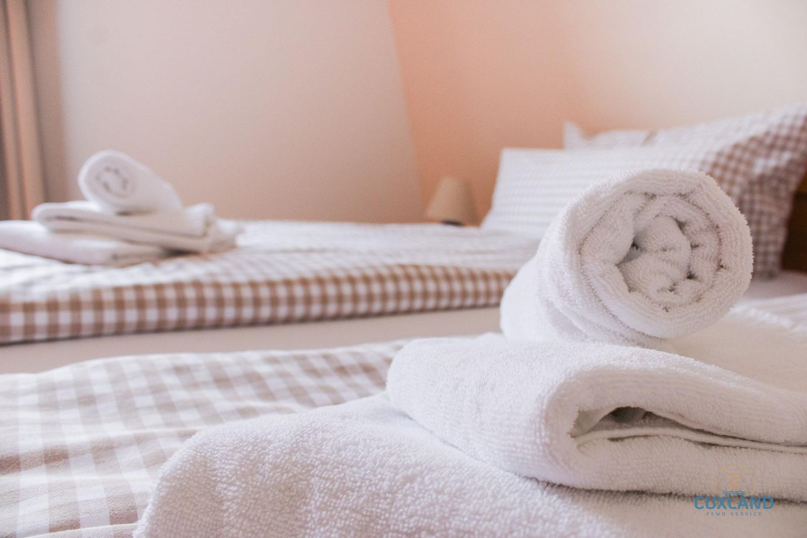 Zwei Betten mit karierten Bettwäsche und gefalteten Handtüchern.