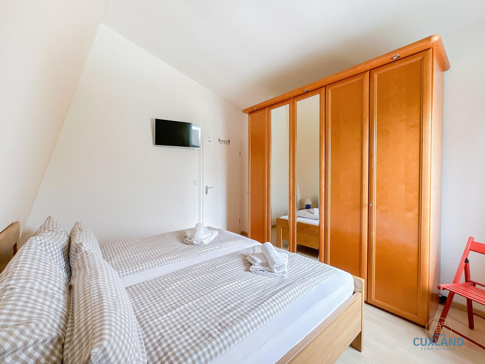 Schlafzimmer mit Doppelbett, Kleiderschrank und TV