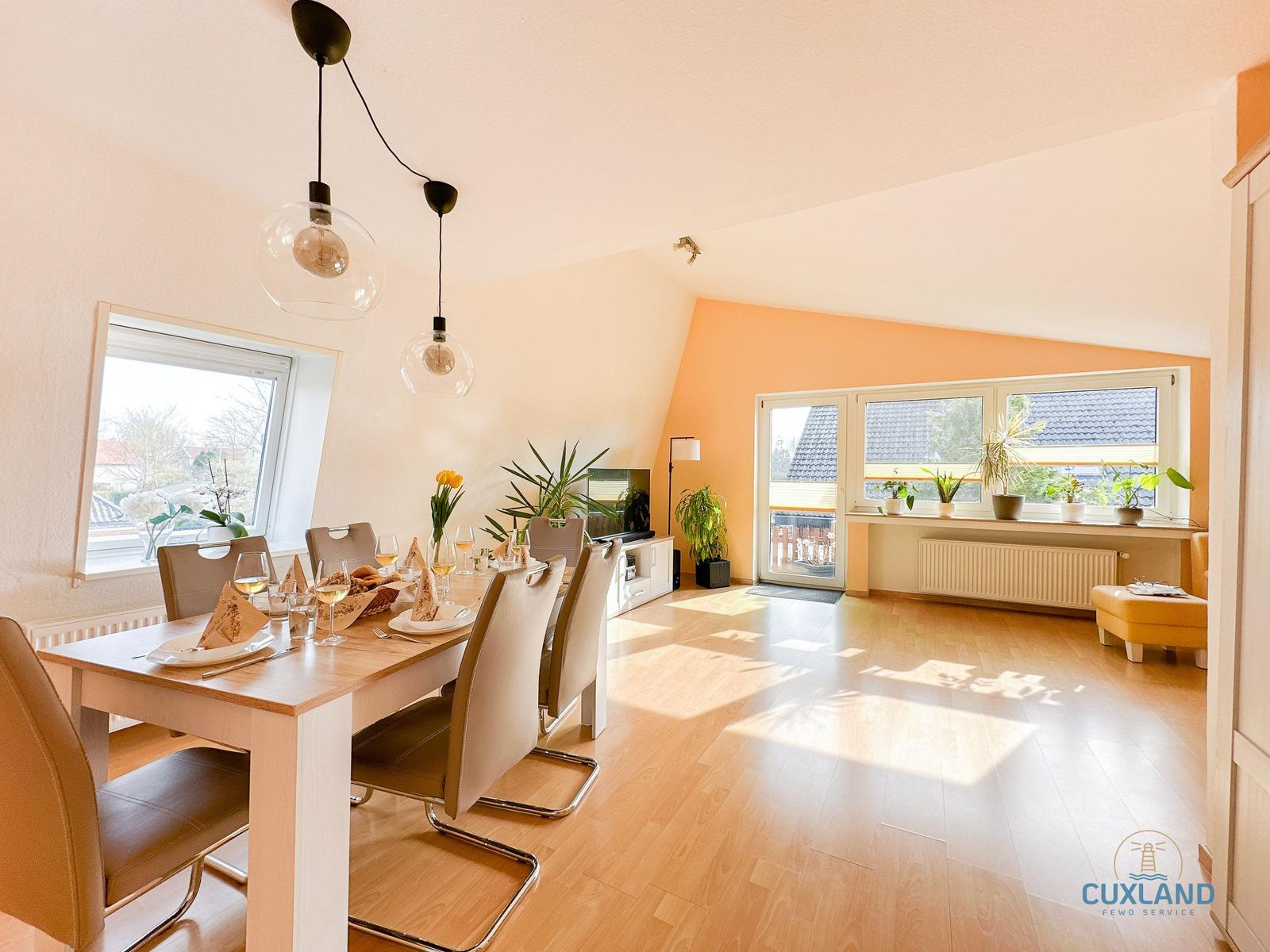 Essbereich mit Tisch, Stühlen und Fenster. Wohnbereich mit Balkontür und Pflanzen.