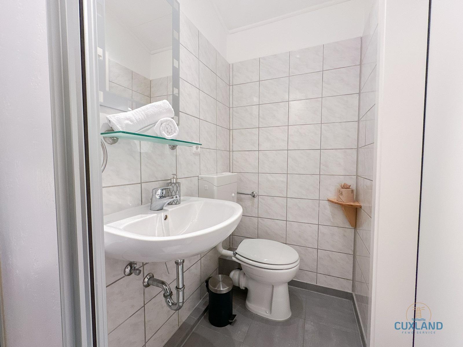 Badezimmer mit Waschbecken, Toilette und Spiegel