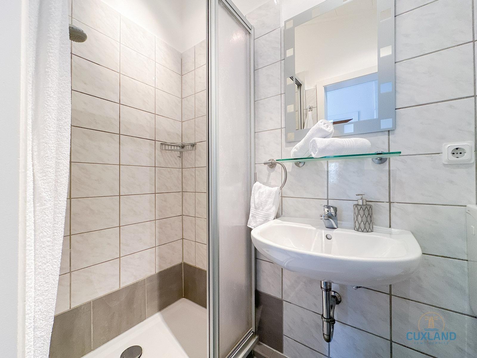 Badezimmer mit Dusche, Waschbecken und Spiegel