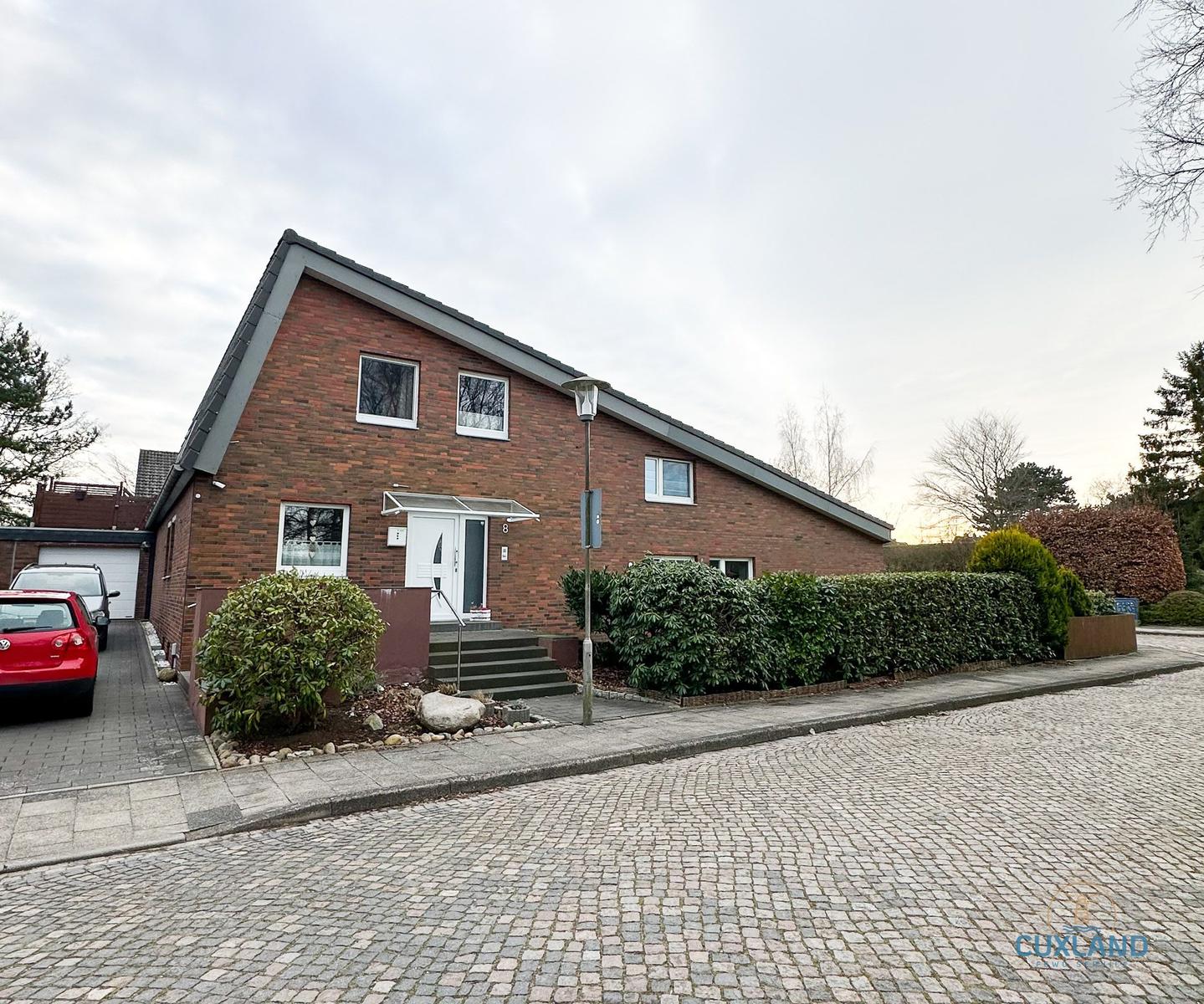 Ein zweistöckiges Haus mit rotem Backsteinfassade und Vorgarten. 