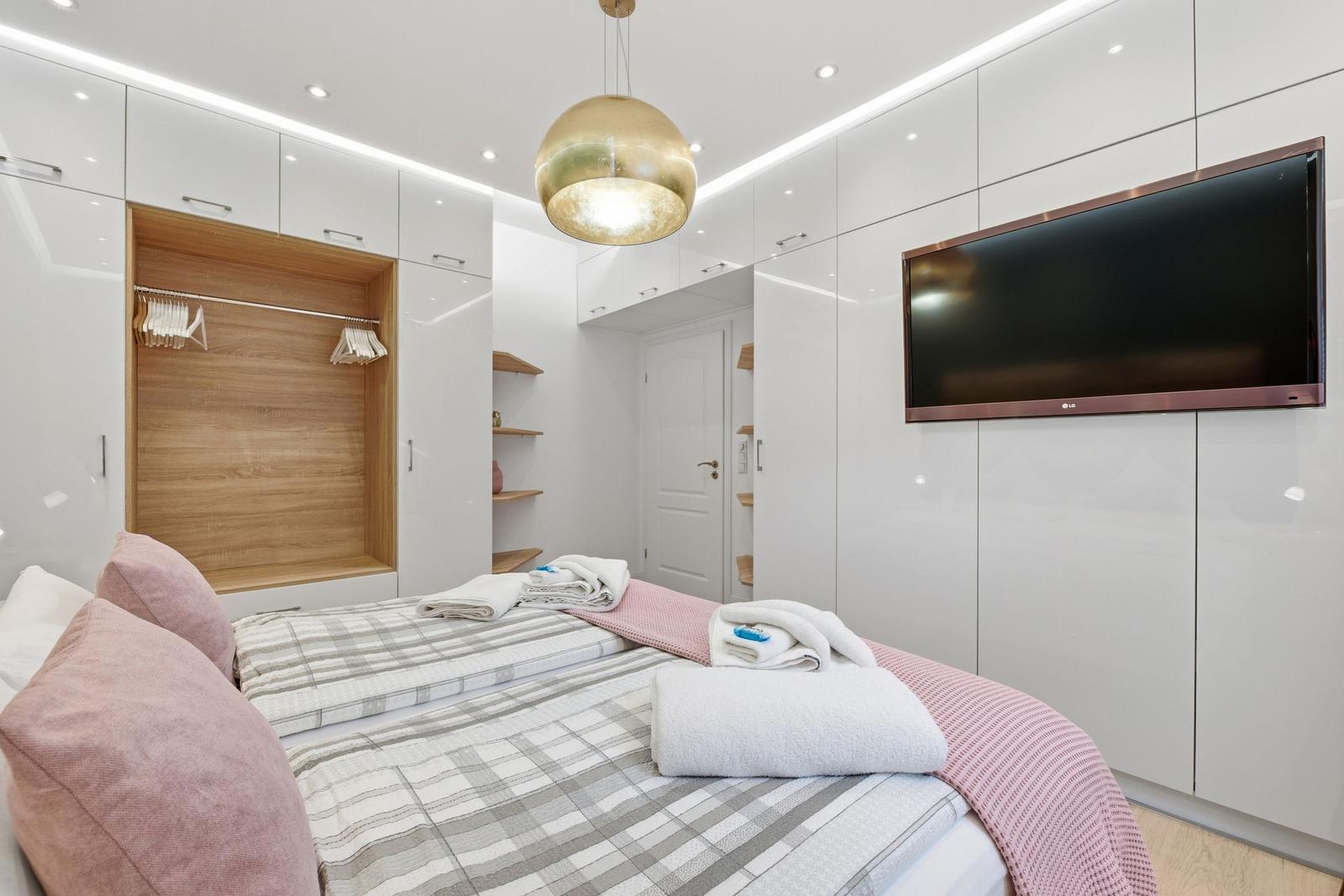Schlafzimmer mit Bett, Kleiderschrank und Fernseher an der Wand.