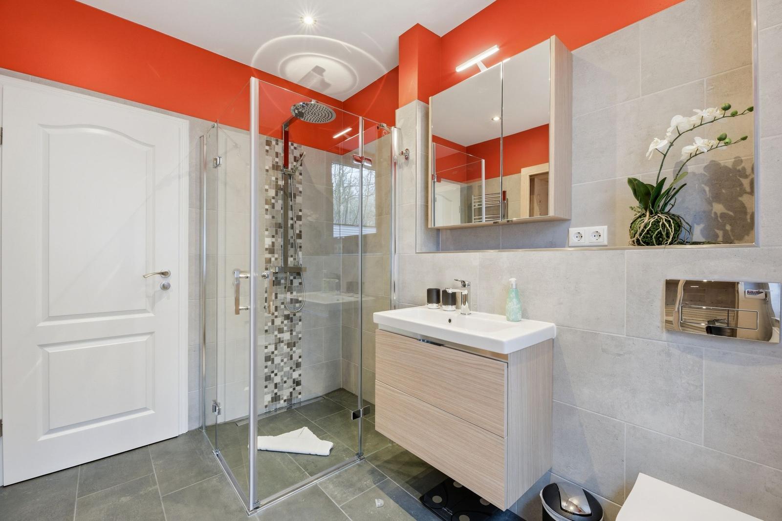 Badezimmer mit Dusche, Waschbecken und Spiegel