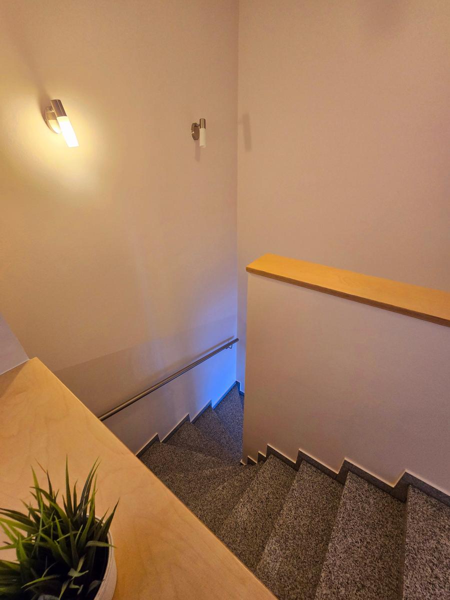 Treppenaufgang zum Obergeschoss der Ferienwohnung mit hellem Wohnambiente.