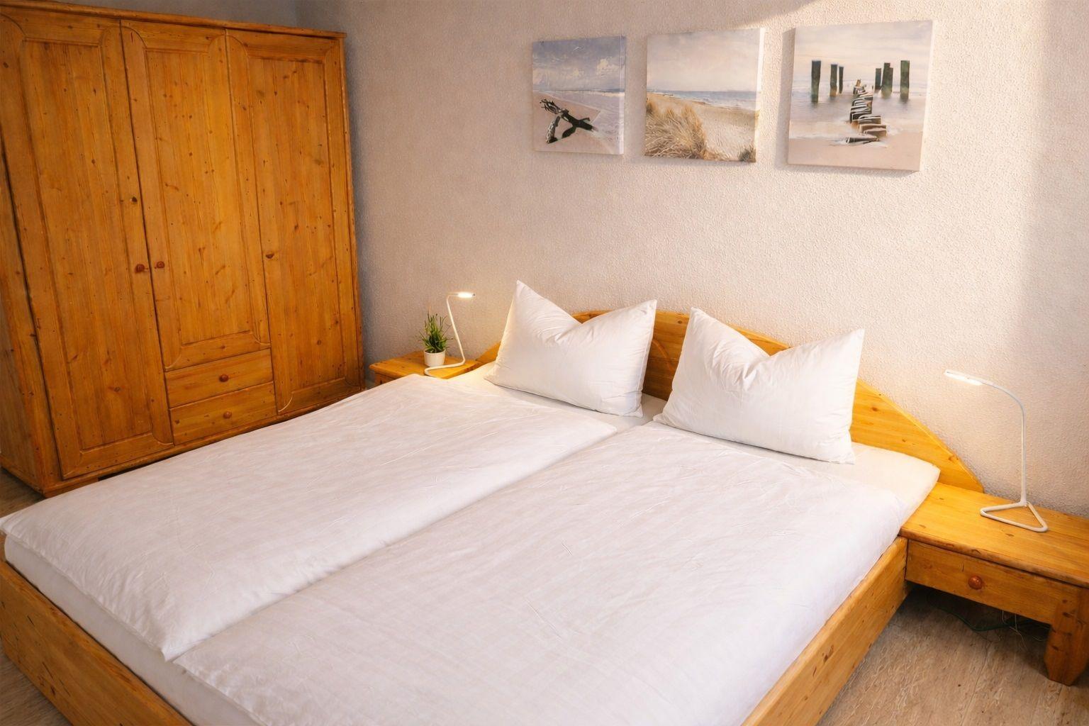 Schlafzimmer mit Holzbett, Kleiderschrank und Wandbildern an der Wand.