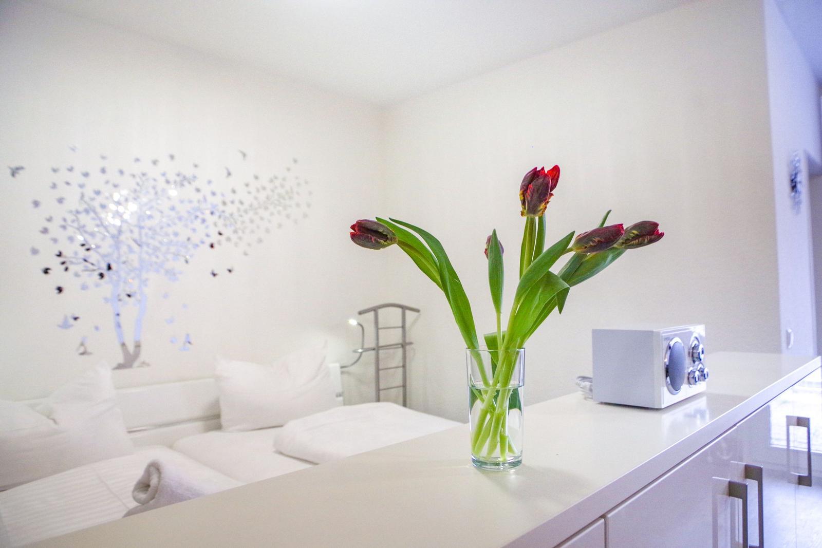 Schlafzimmer mit Bett, Blumen und Wanddekoration