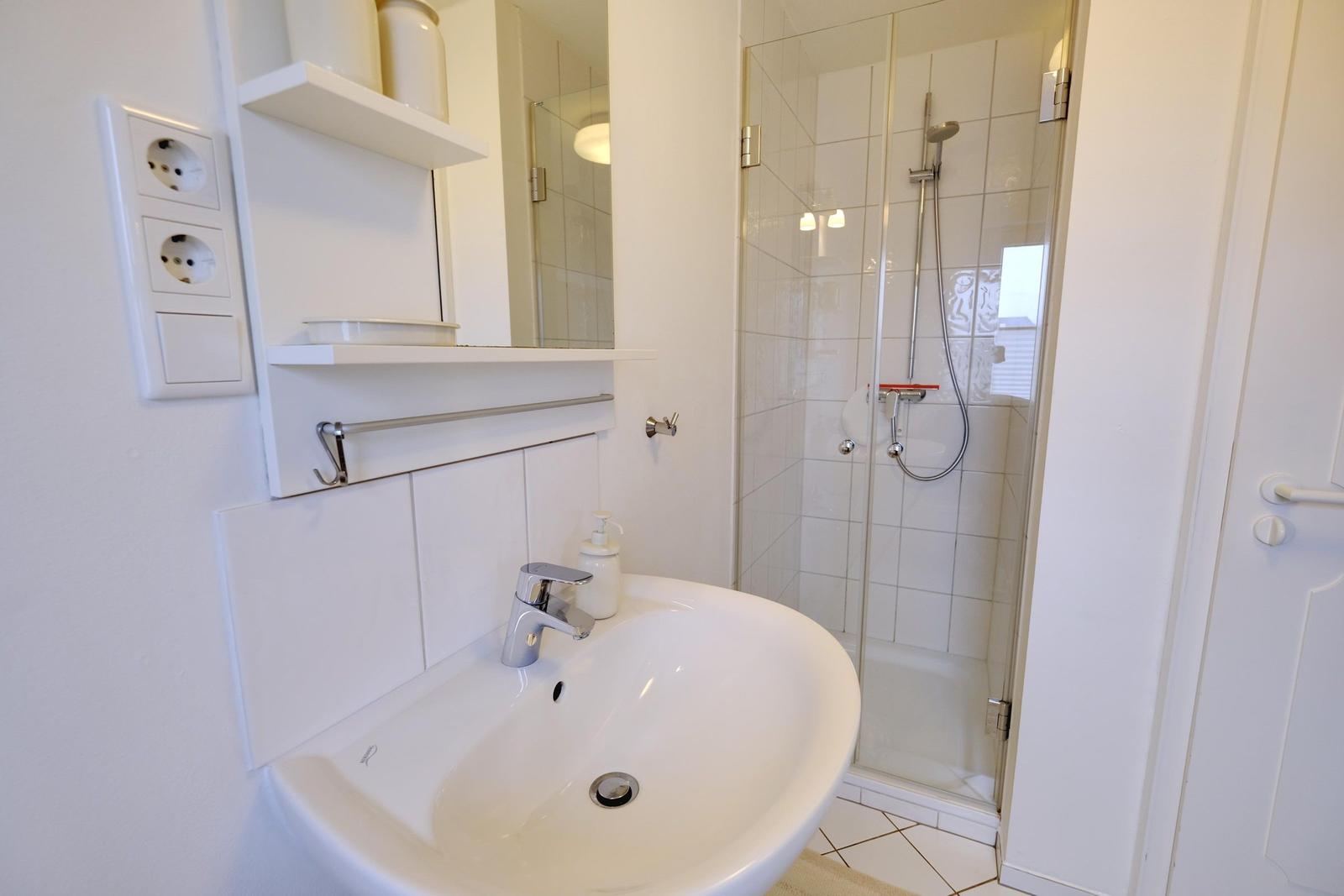 Badezimmer mit Waschbecken, Spiegel und Dusche.