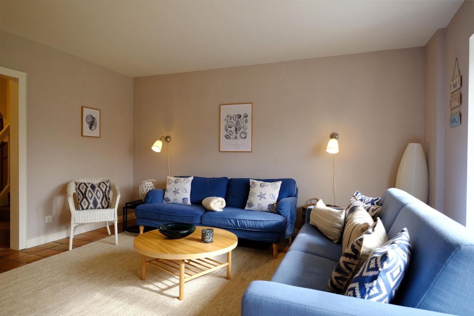 Wohnzimmer mit blauem Sofa, runden Tisch und Wandbildern