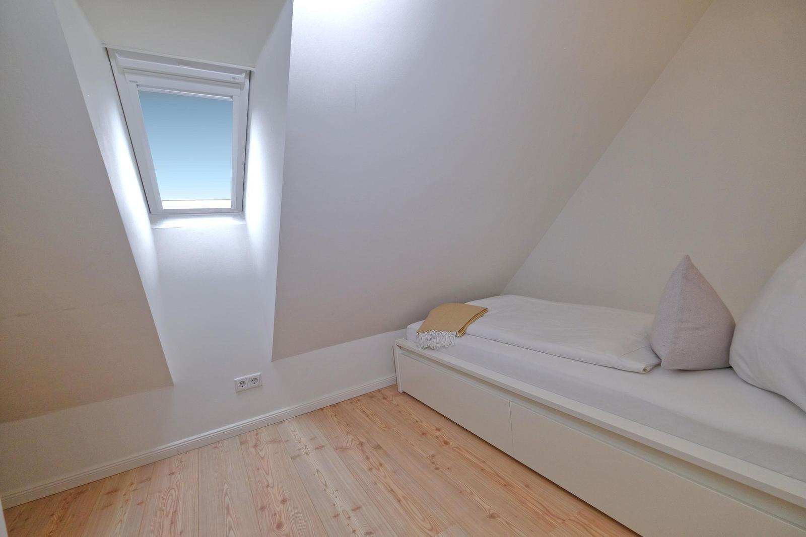 Dachgeschosszimmer mit Fenster und Bett