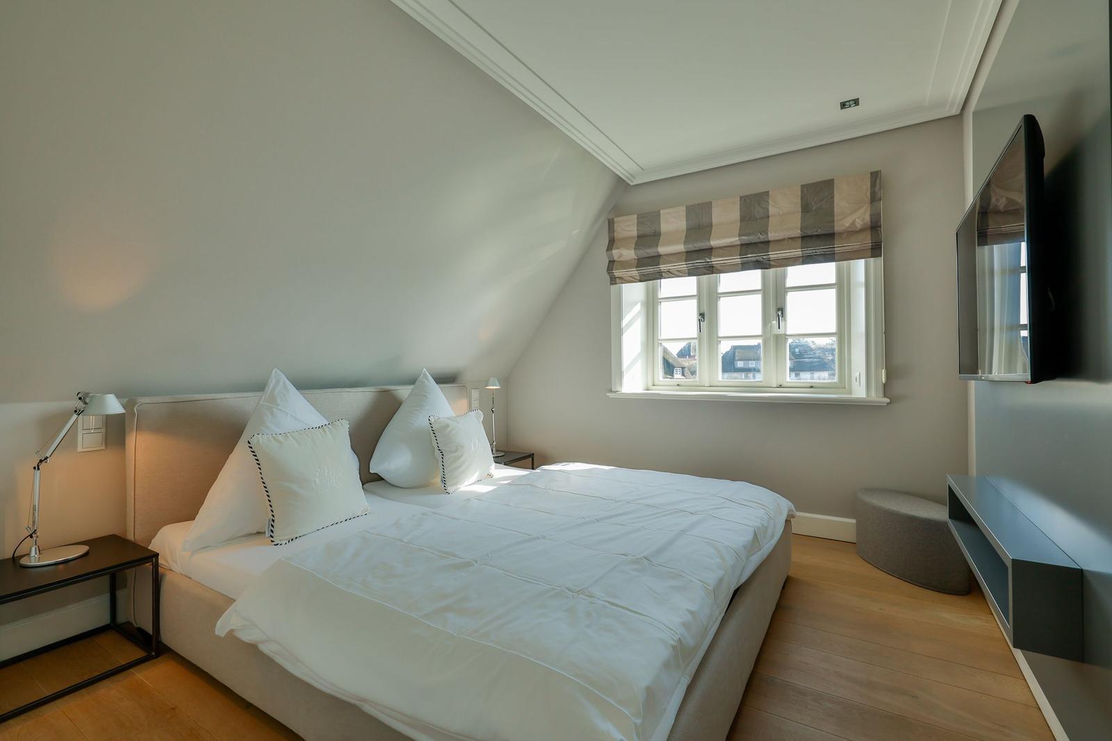 Schlafzimmer mit Dachschrägen, Bett, Fenster und Fernseher