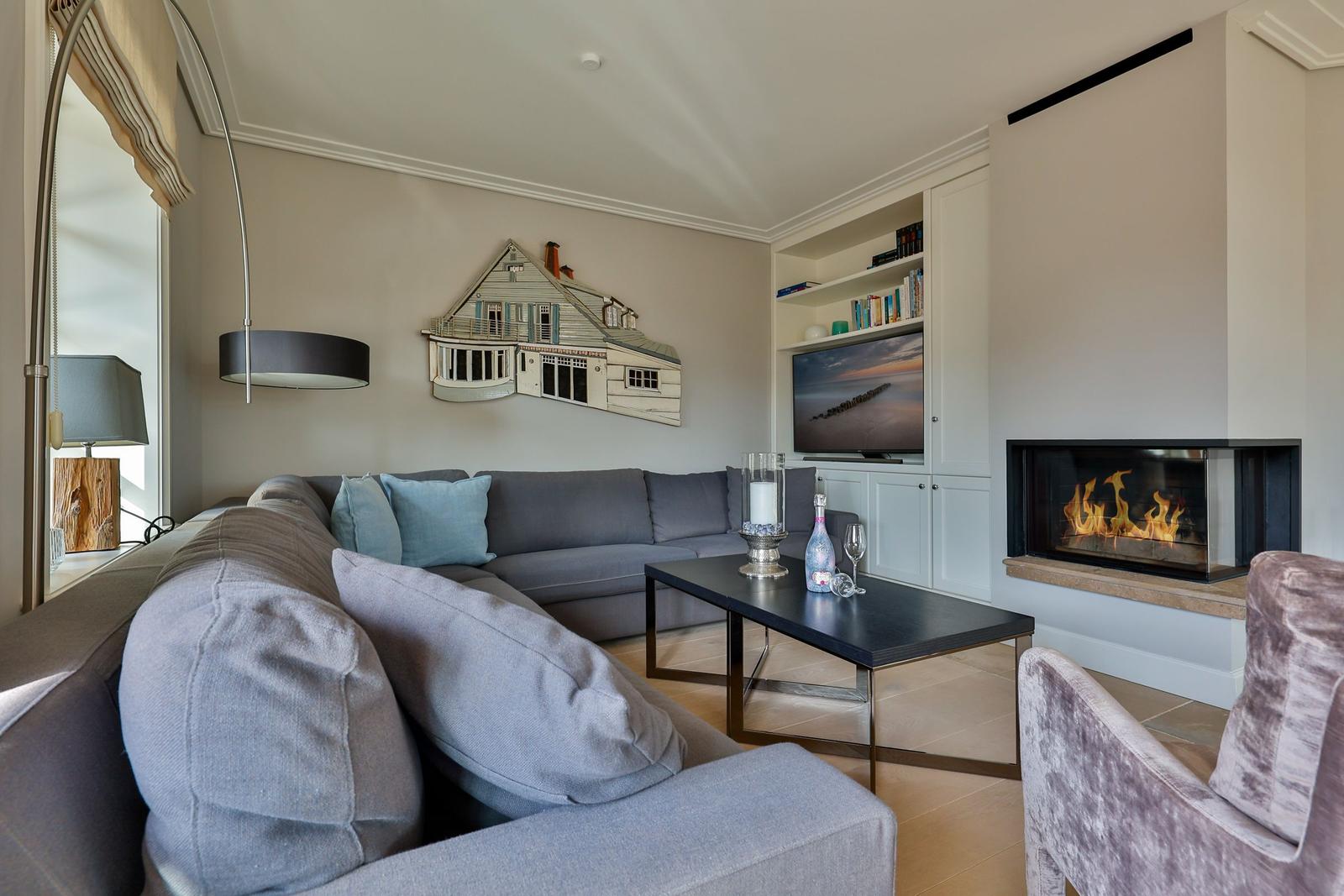 Wohnzimmer mit Sofa, Kamin und Fernseher an der Wand.