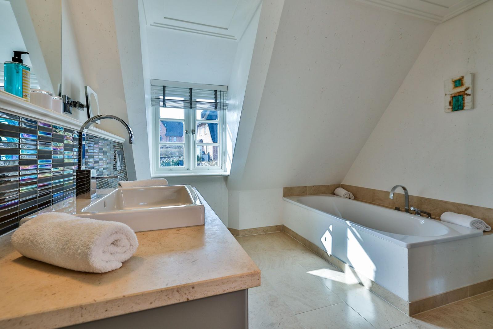 Badezimmer mit Badewanne, Waschbecken und Fenster