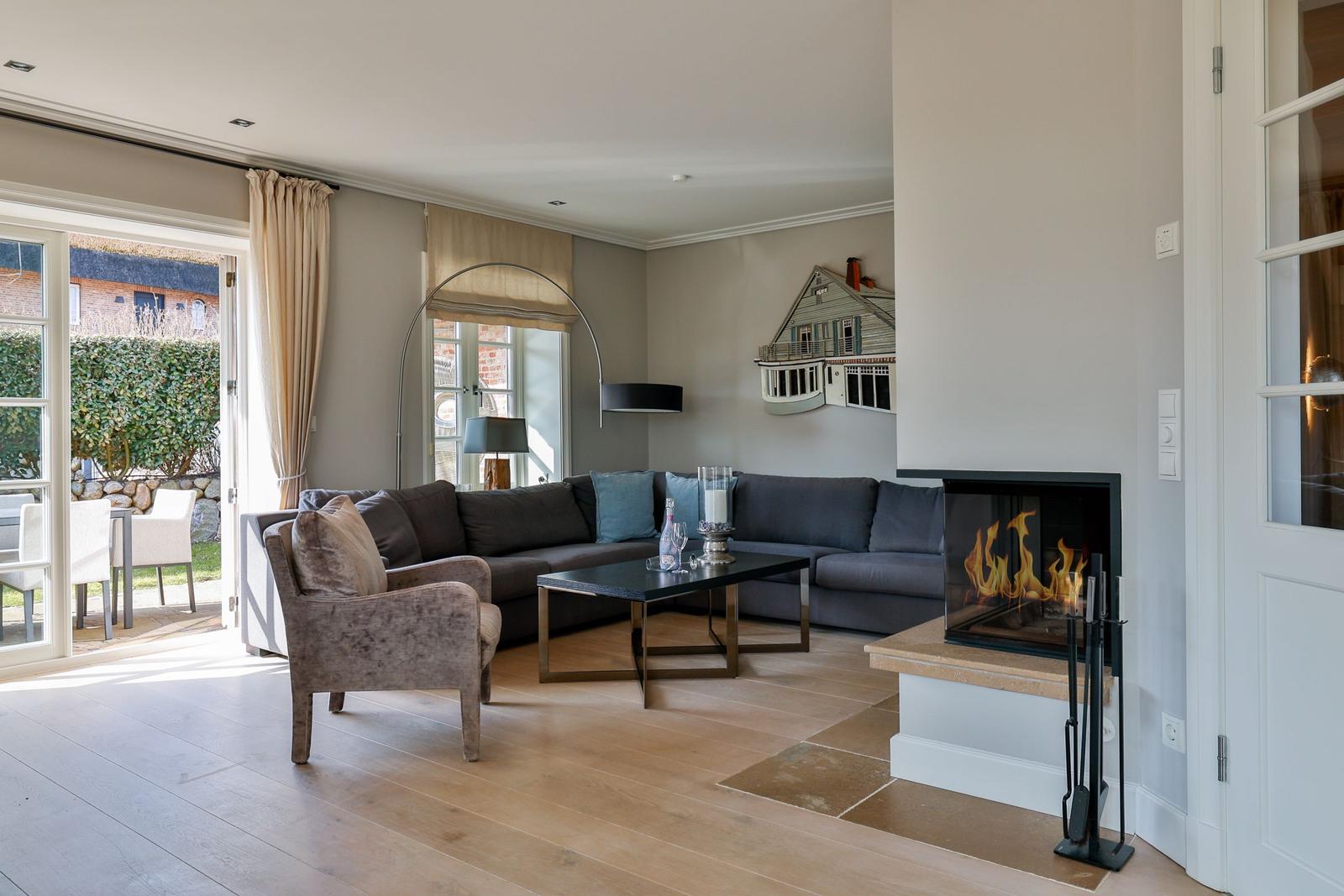 Wohnzimmer mit Kamin, Sofa und Terrassentür
