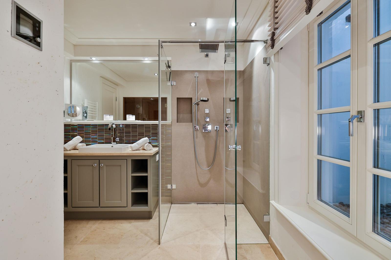 Dusche mit Glaswand, Waschbecken mit Spiegel und Fenster