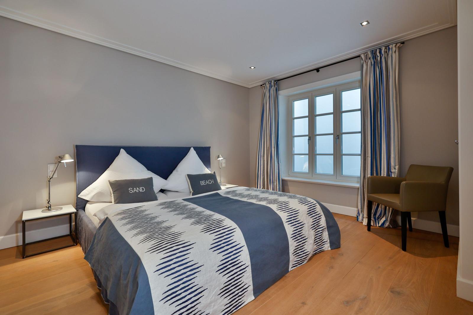 Schlafzimmer mit Bett, Fenster und Stuhl.