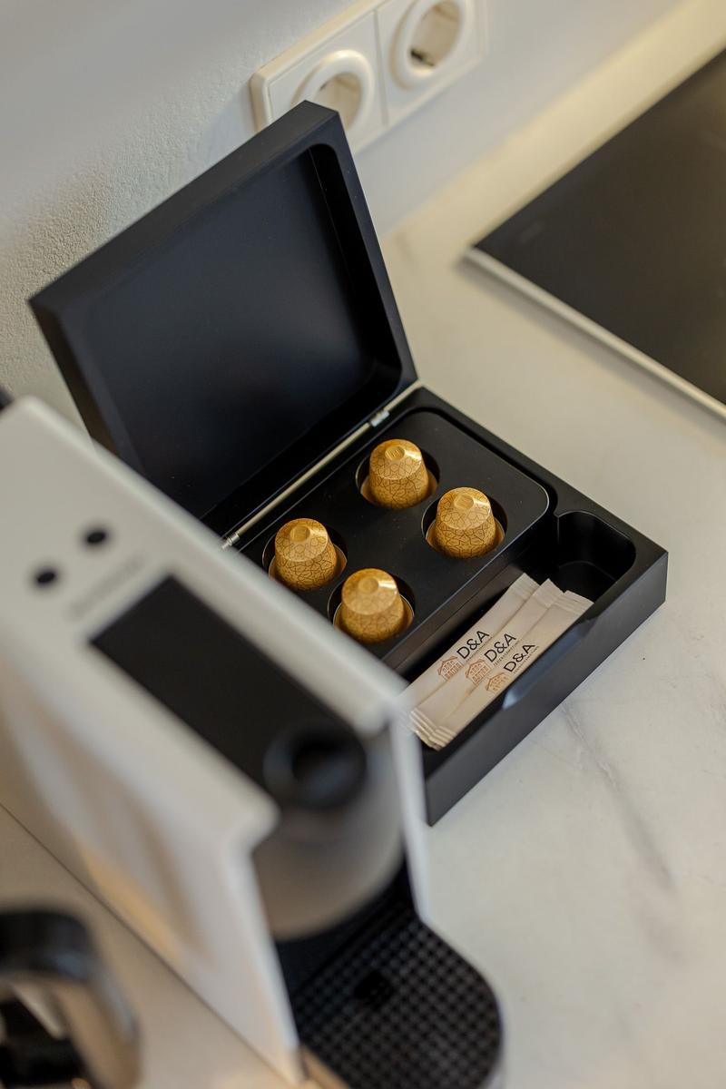 Coffee machine with four capsules and sugar packets on countertop