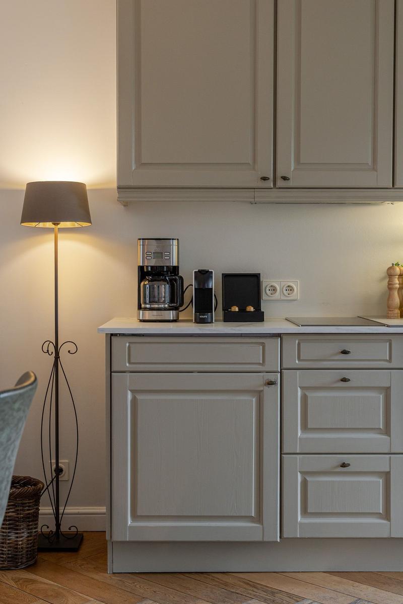 Kitchen area with light cabinets, coffee machine, and wall sockets.