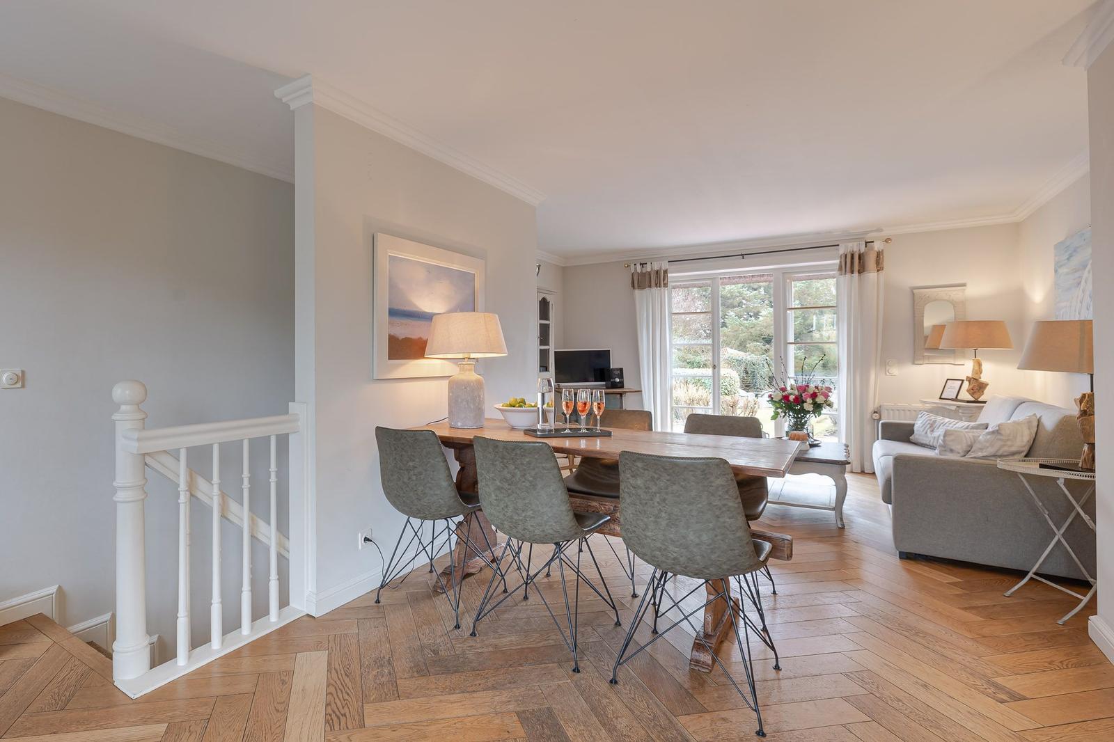 Dining area with table and chairs, living area with sofa and garden view