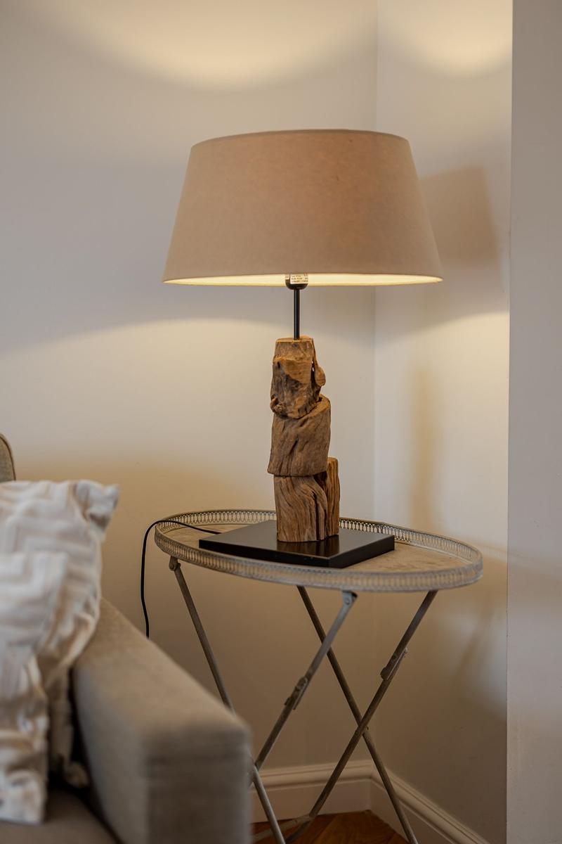 Table lamp with wooden base on a metal table next to a sofa.