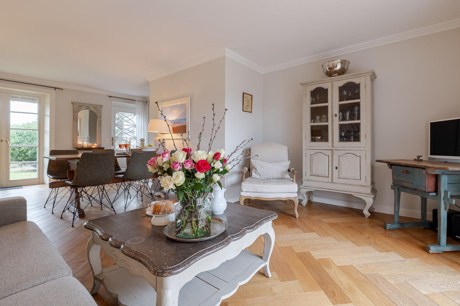 Living and dining area with wooden floor, dining table, sofa, and sideboard.