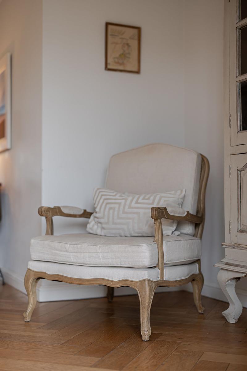 Antique chair with cushion in living area with wooden floor and wall picture.