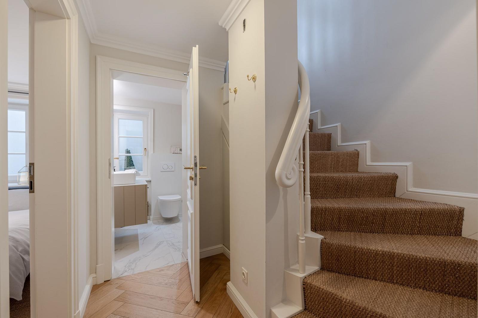 Staircase with carpeted steps and view into bathroom with bathtub and toilet.