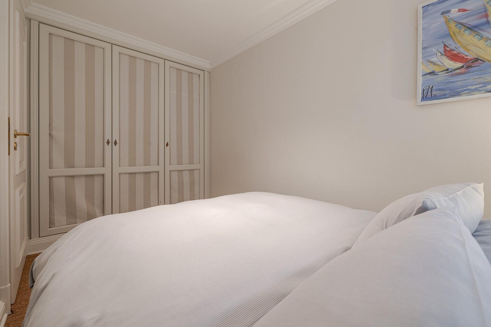 Bedroom with bed, wardrobe, and wall art featuring boats.