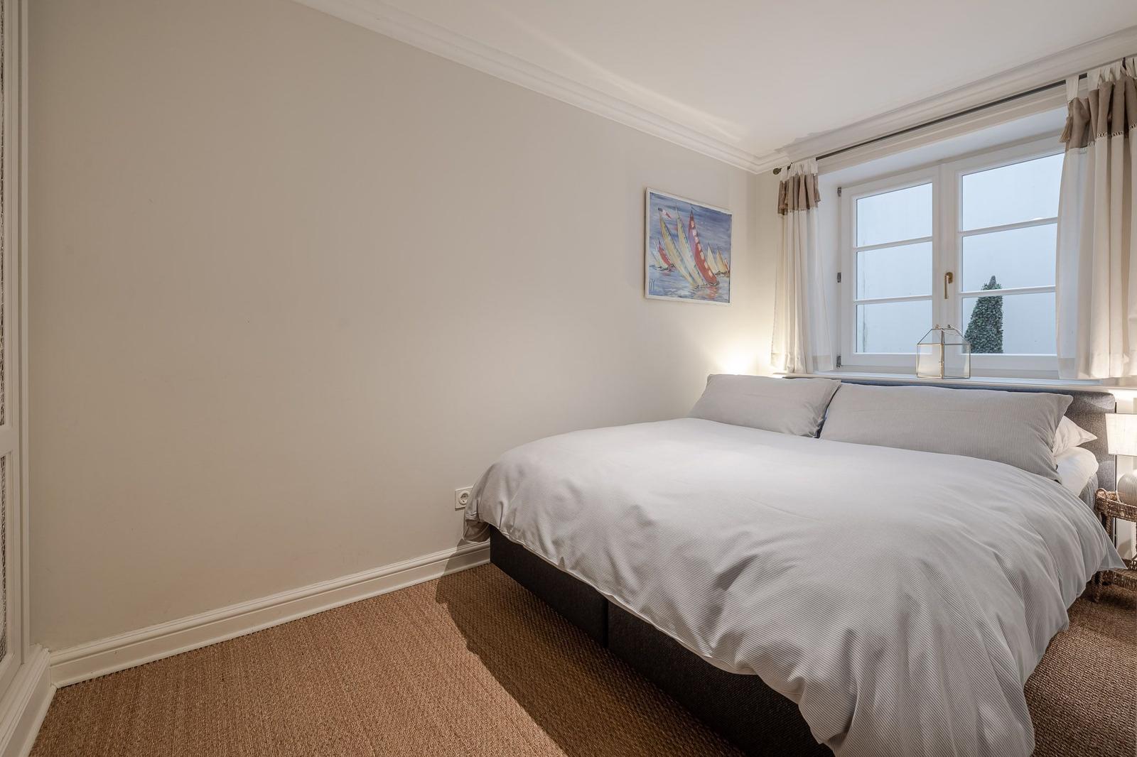 Bedroom with bed, window, and wall picture.
