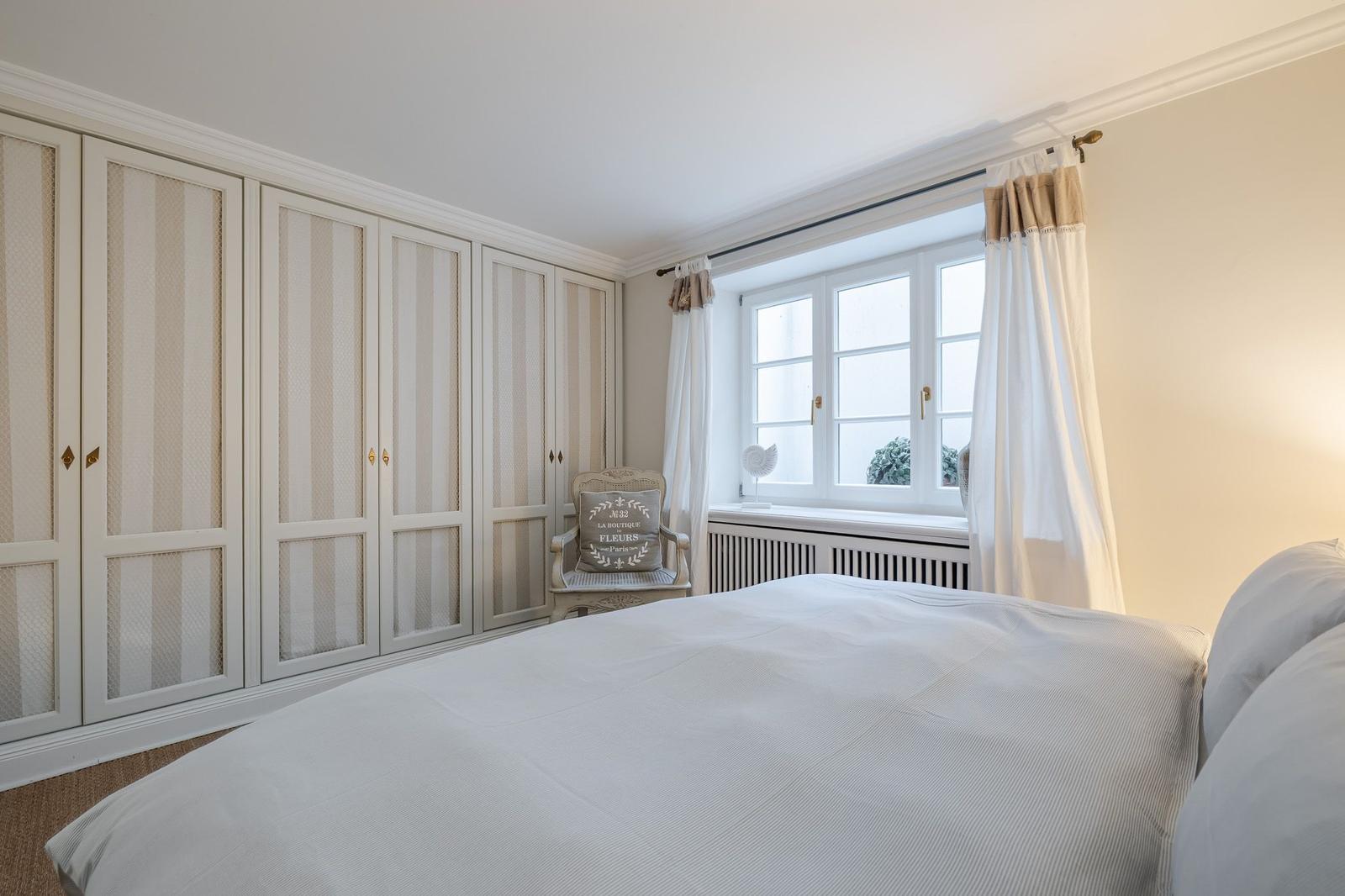 Bedroom with bed, wardrobe, and window with curtains.