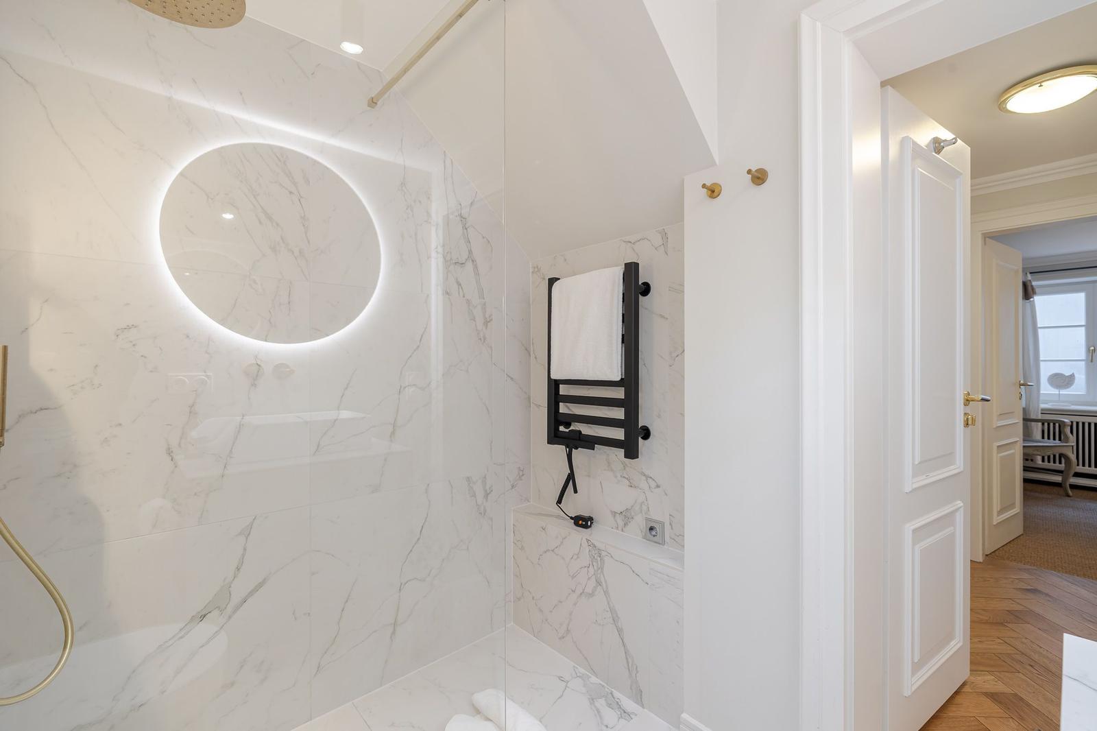Shower with round mirror and heater, white marble wall