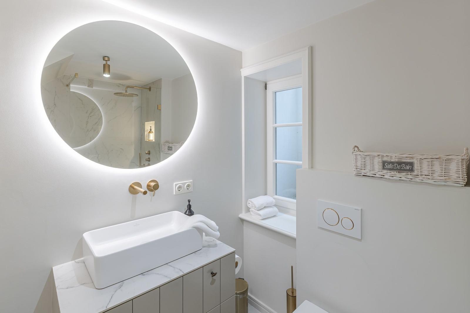 Bathroom with round mirror, sink, and window