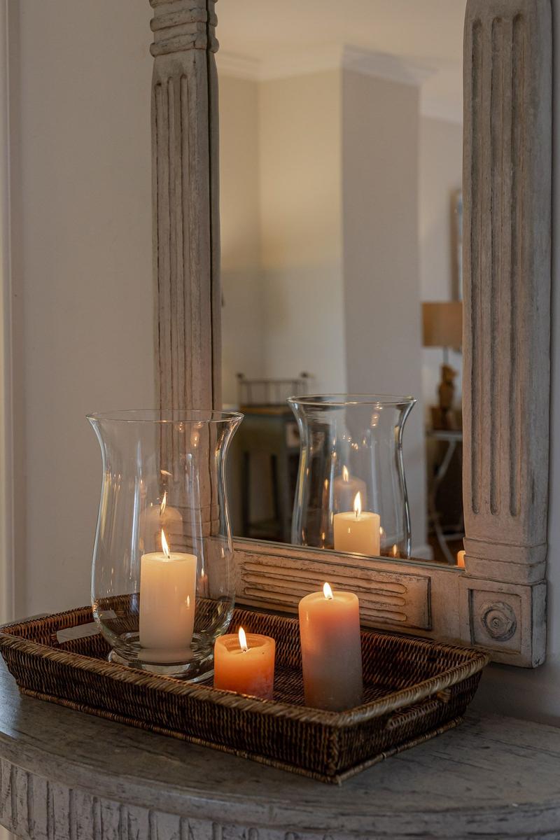 A basket with lit candles sits in front of a mirror with a wooden frame.
