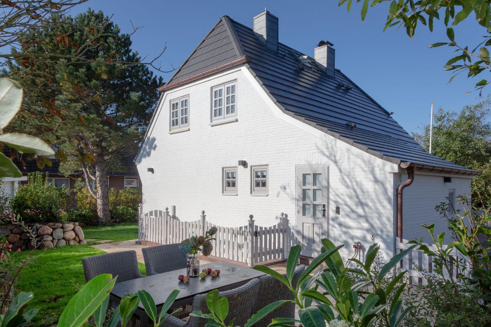White house with dark roof, garden area, and seating.
