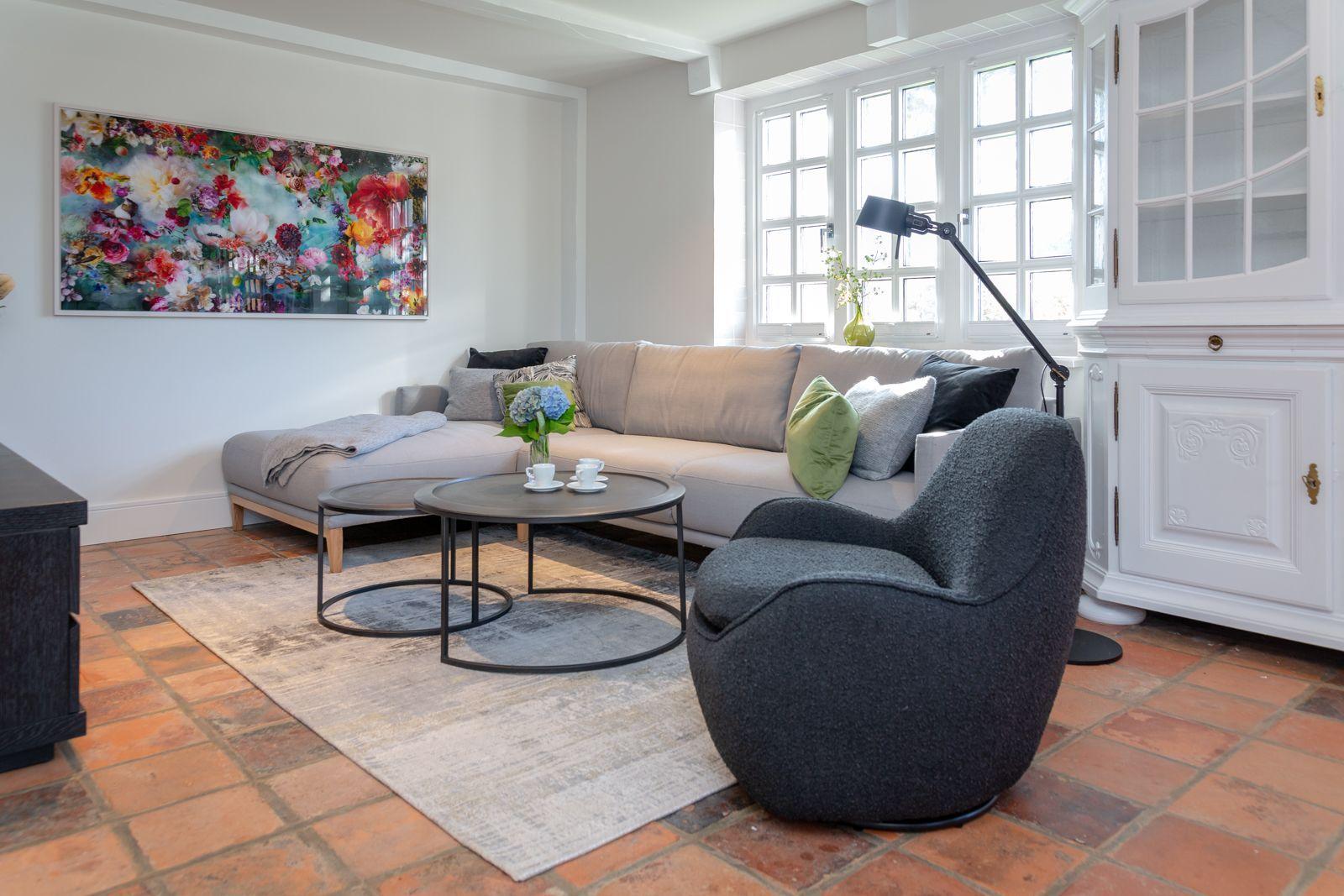 A living room with sofa, armchair, table, and wall art.