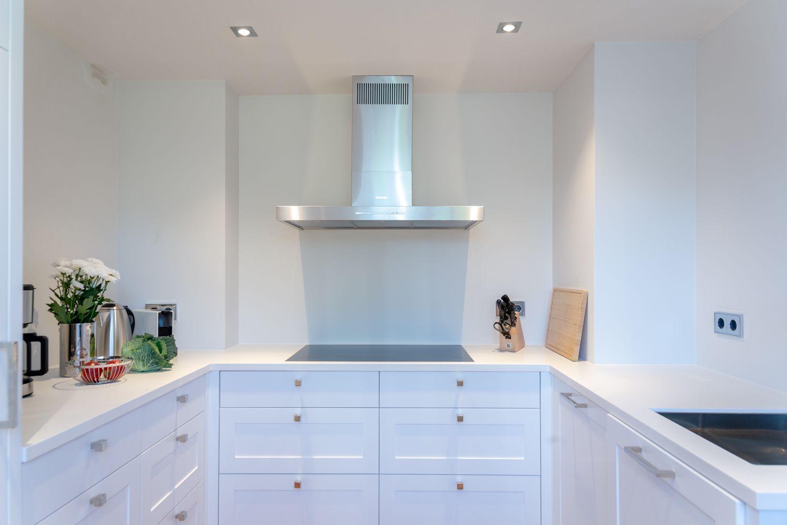 Modern kitchen with white cabinets and stainless steel range hood.